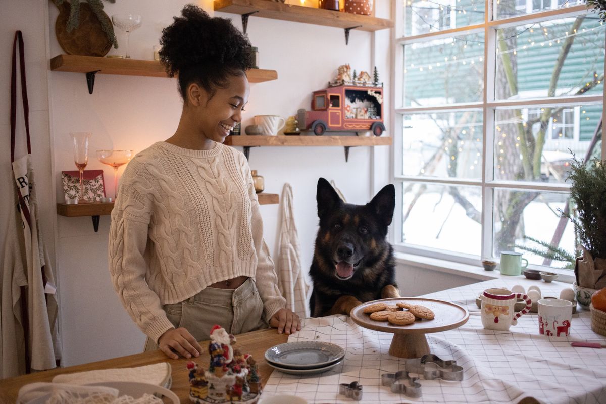 Woman baking in the kitchen, with a German Shepherd next to her watching attentively
